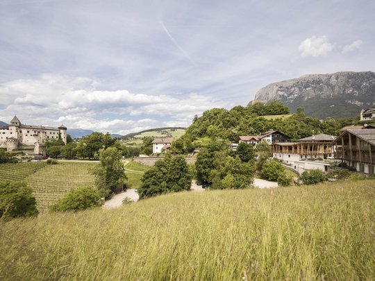 Presulis: Ihre Luxus-Ferienwohnung in Völs am Schlern Landschaft mit Schloss, grünen Wiesen und Bergen bei klarem Himmel
