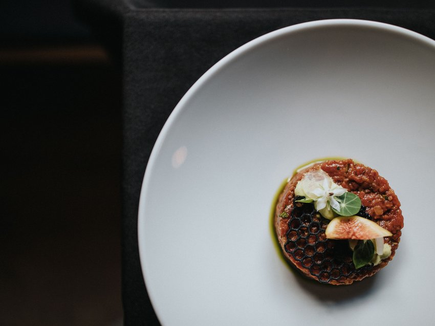 Pure indulgence in our restaurant in Völs am Schlern Artfully plated gourmet dish with flower and fig on white plate
