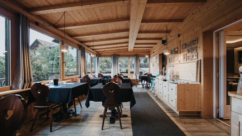 Presulis: Ihre Luxus-Ferienwohnung in Völs am Schlern Gemütliches Restaurant mit Holzmöbeln und schwarzen Tischdecken