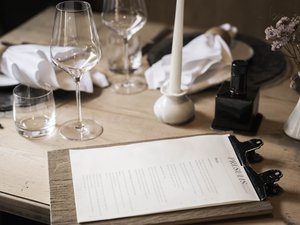 Pure indulgence in our restaurant in Völs am Schlern Elegant dining table set with wine glasses and menu