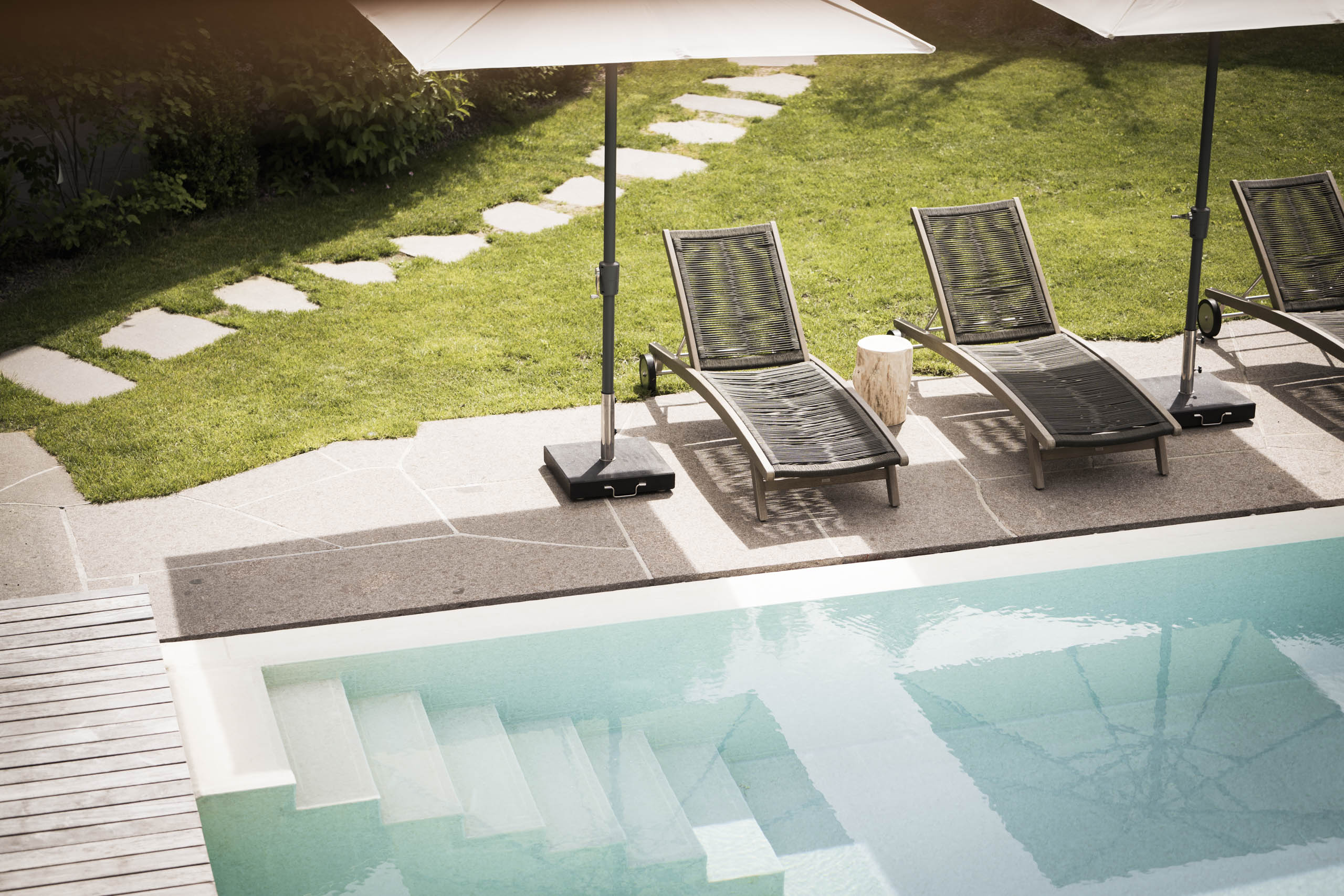 Presulis: Ihre Luxus-Ferienwohnung in Völs am Schlern Leere Liegestühle mit Sonnenschirmen neben einem Swimmingpool im Garten