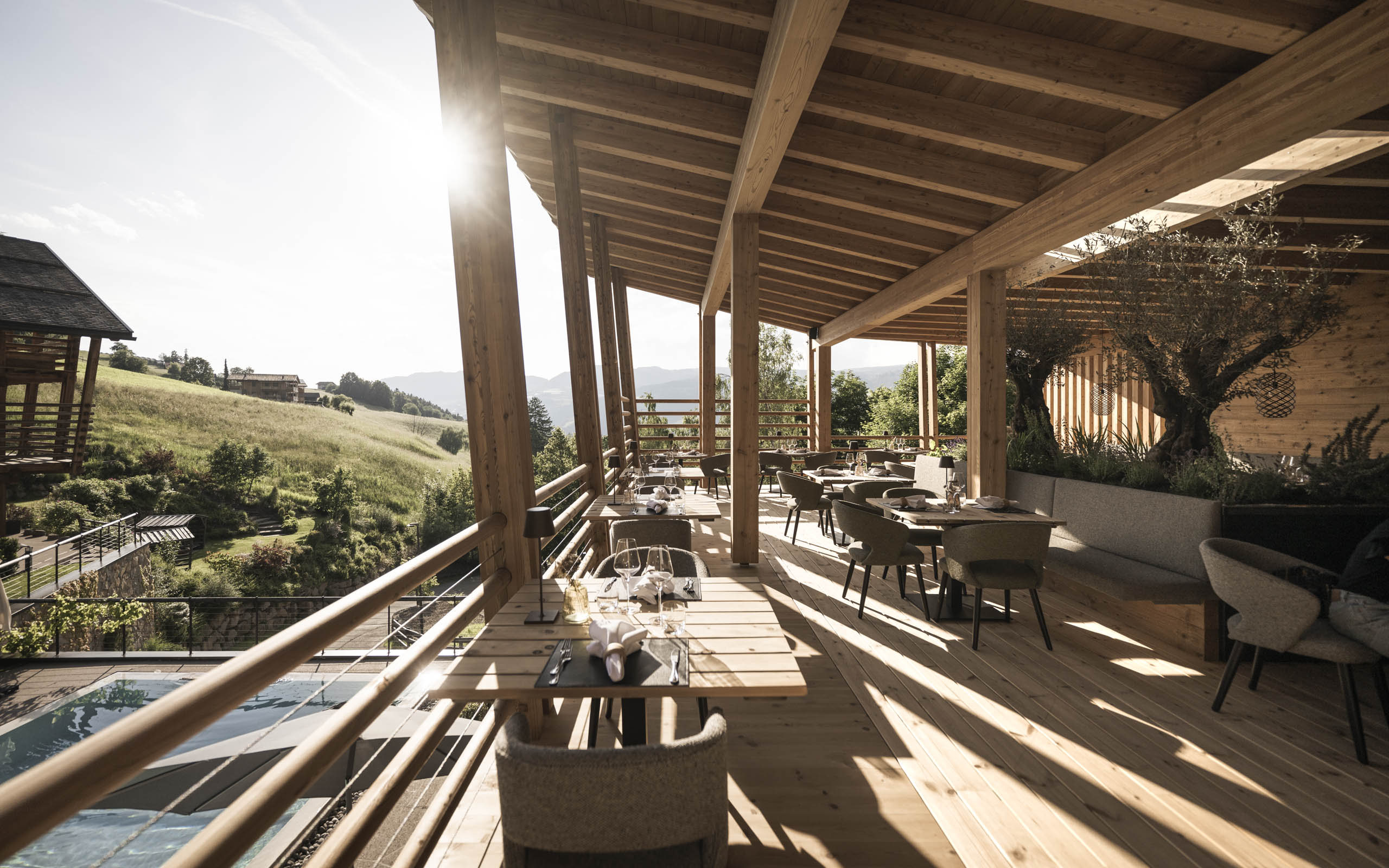 Presulis: Ihre Luxus-Ferienwohnung in Völs am Schlern Holzüberdachte Terrasse mit gedeckten Tischen und Blick auf grüne Hügel